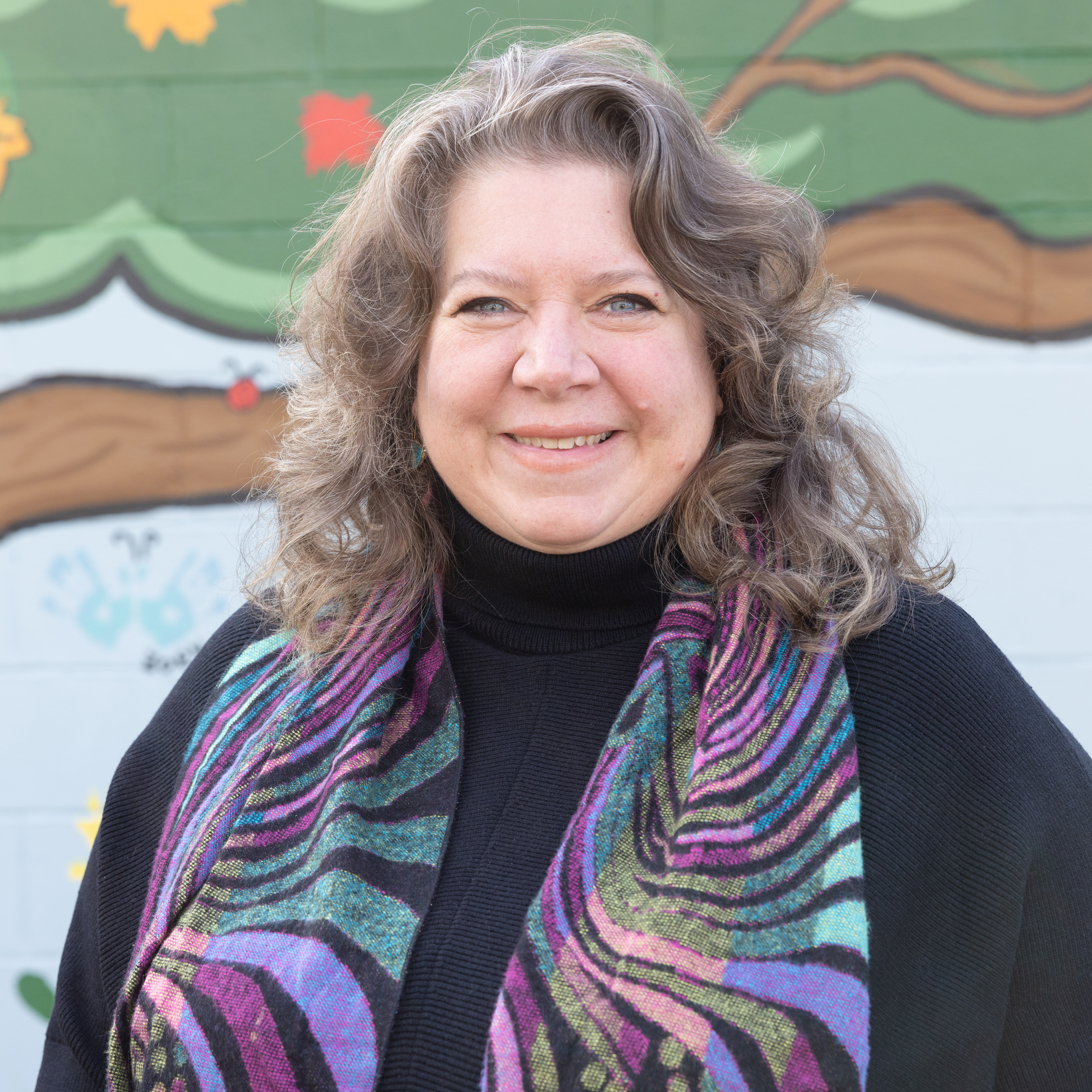 Photo of faculty member in front of a mural